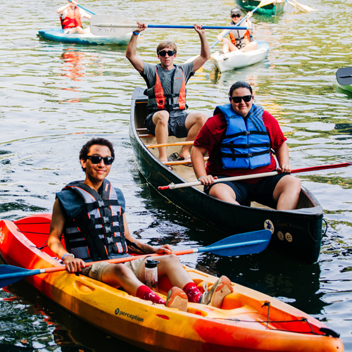 Group of students smiling as they float down the Saluda River in kayaks.