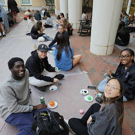 group of students sitting on a sidewalk