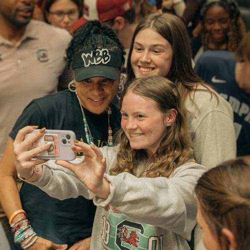 Coach Dawn Staley taking a photo with Honors students