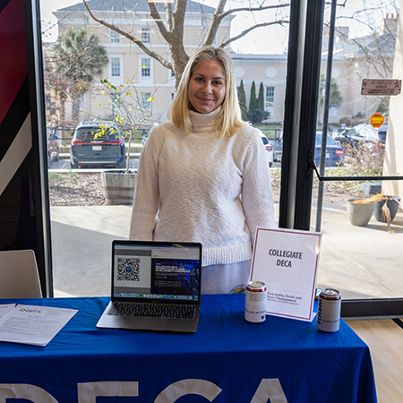 A member of Collegiate DECA poses at a student organization fair