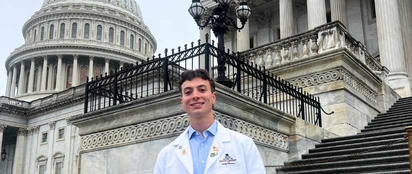Student in white coat posing in front of capitol building