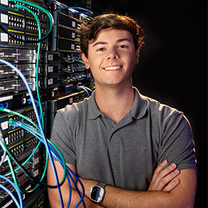 Braden Guliano stands next to a rack of computer equipment
